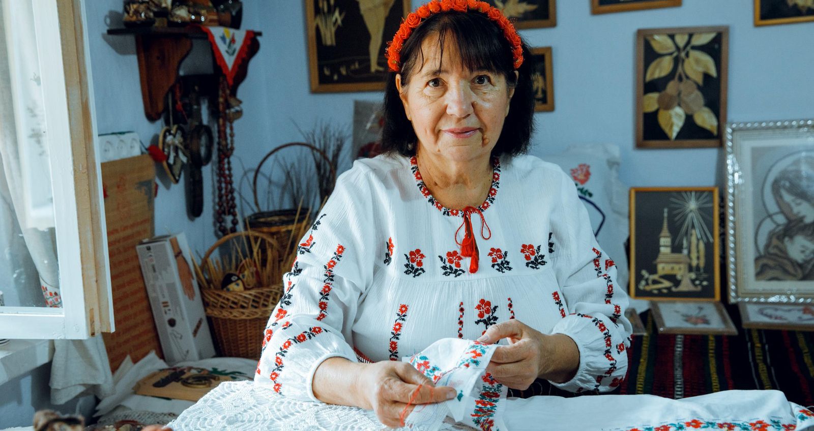 Meșteriță în ie brodată lucrând la o broderie, în atelierul ei